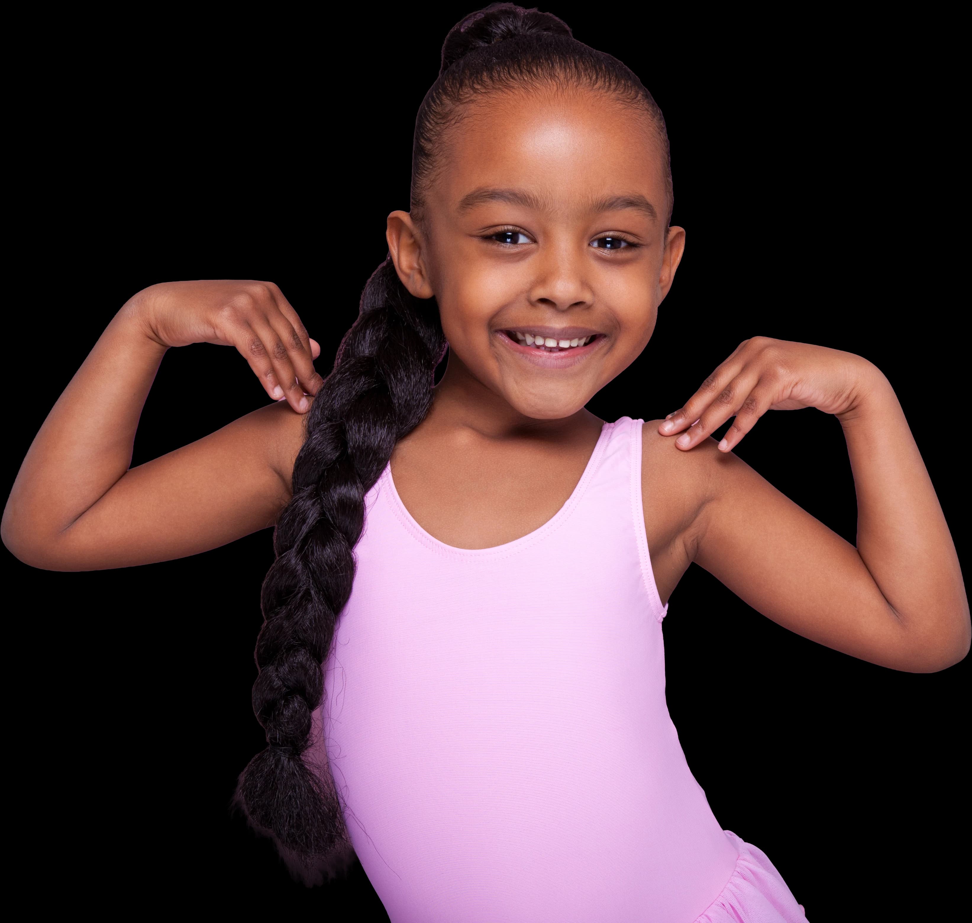 Une petite fille en justaucorps rose, souriante, les mains sur les épaules
