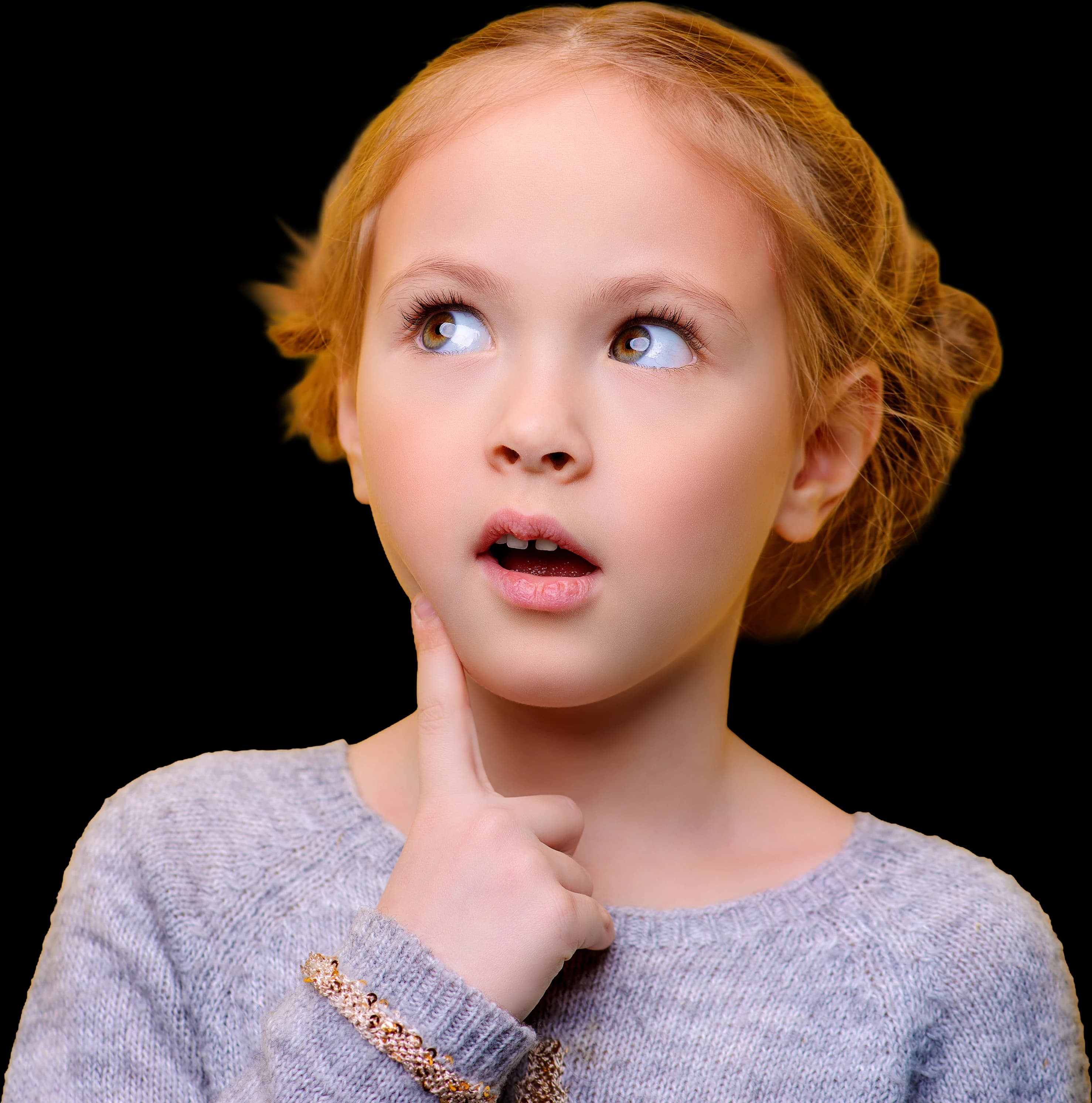 Une petite fille rousse, le doigt sous le menton, qui réfléchit